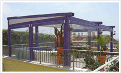 Metalmark infissi a Roma presenta Tenda da sole STOMBOLI: Struttura in alluminio addossata a parete con trave frontale di appoggio verniciata con polveri per esterni. Versione inclinata, viene fornita di serie nella colorazione tinta legno. Colorazione RAL e micaceo disponibili a richiesta. Completata da una tenda mobile resistente a piaggia e vento e accessori. Struttura completa di tettino di protezione, impacchettamento tenda, tettino copriguida, gronda  e pluviale, motore con radiocomando. Dimensioni Massime: L 1300 X S 600